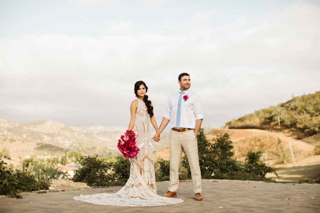 Fiesta inspired outdoor wedding bride in a boho macrame dress and groom with pink flowers