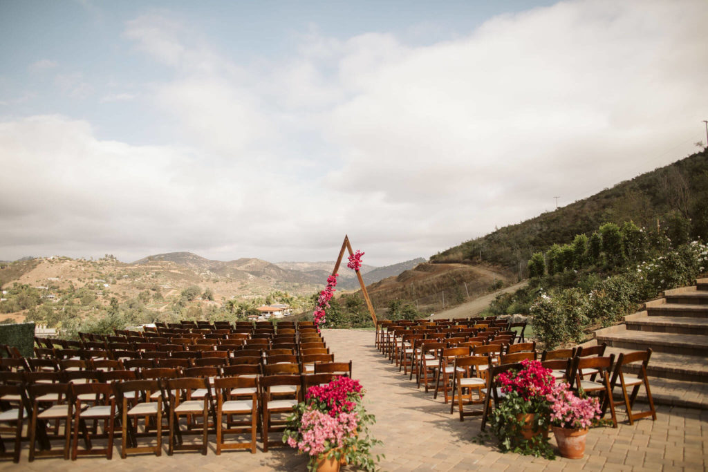Fiesta inspired outdoor wedding triangle arch with pink flowers and potted bougainvillea