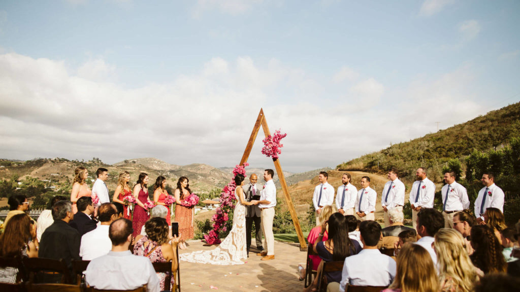 Fiesta inspired outdoor wedding ceremony triangle arch with pink flowers
