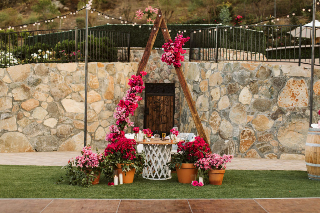 Fiesta inspired outdoor wedding sweetheart table with pink flowers and potted bougainvillea