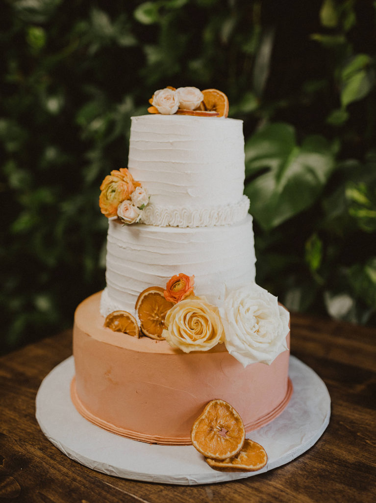 Simple fall wedding cake with orange white and yellow flowers with citrus slices at The Wood Shed in Vista California