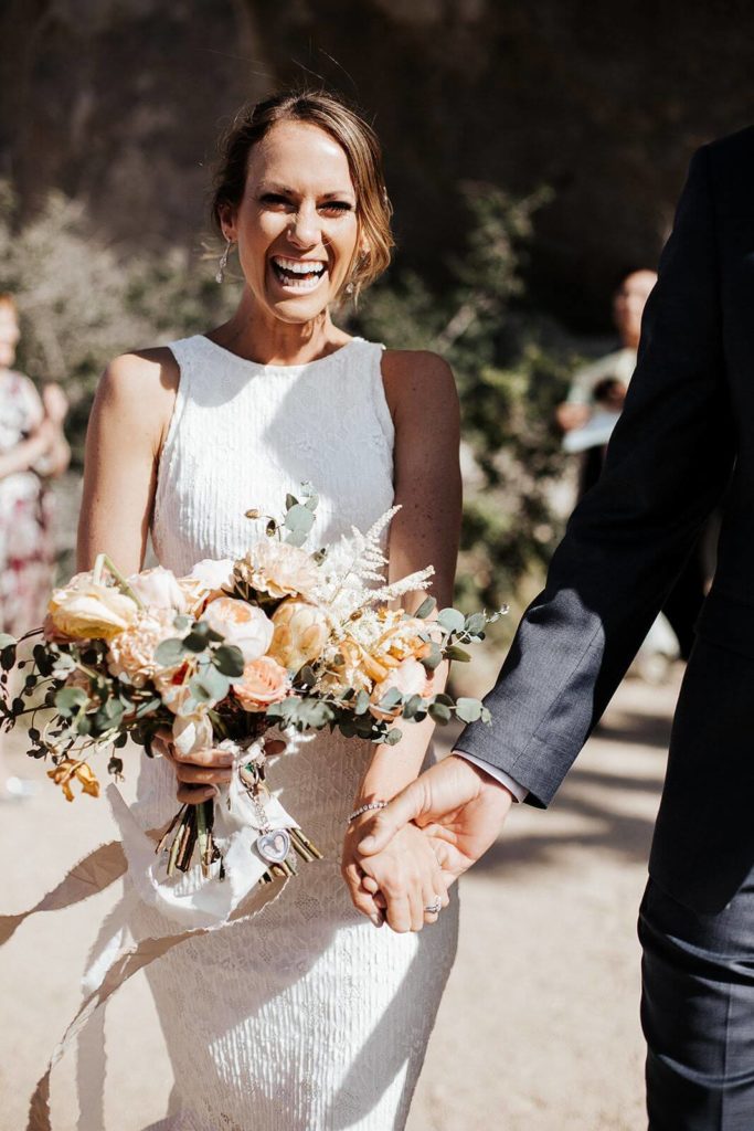 Bride laughing with peach and white bridal bouquet in Joshua Tree