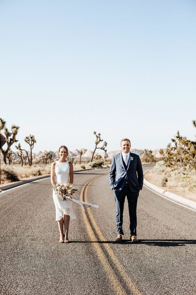 Bride and groom standing in an empty highway in Joshua Tree