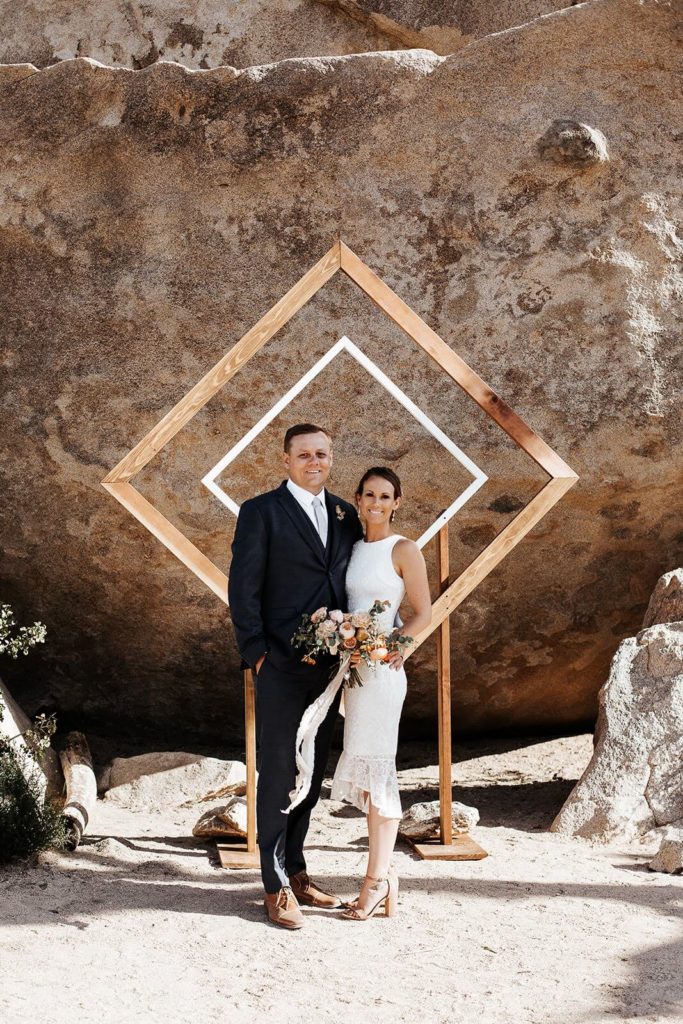 Wedding ceremony geometric arch with bride and groom in Joshua Tree
 