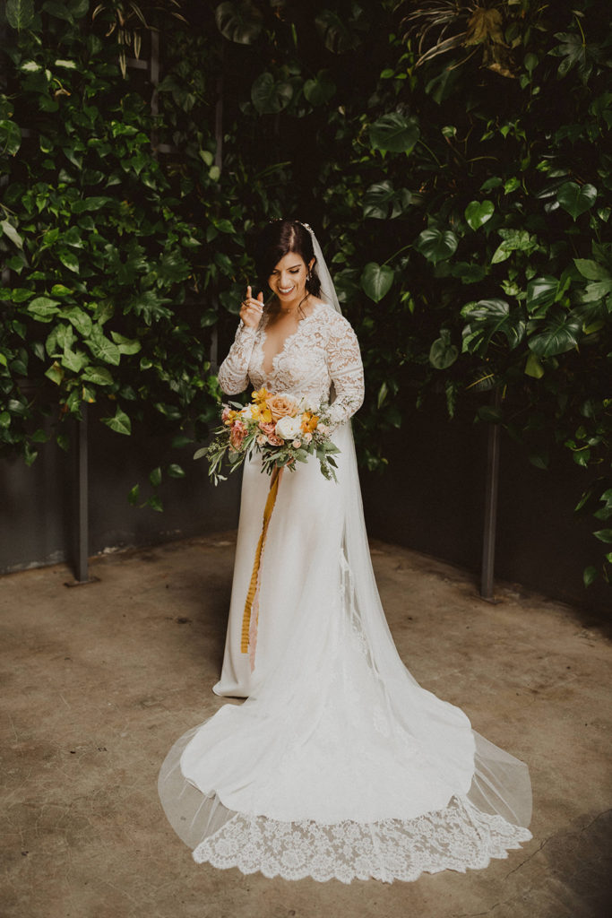 Fall wedding bride holding her colorful bouquet with orange yellow and mauve flowers at The Wood Shed in Vista California
