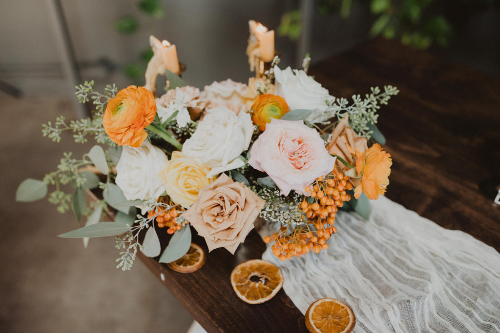 Fall wedding centerpiece with orange white and yellow flowers and citrus slices at The Wood Shed in Vista California 
