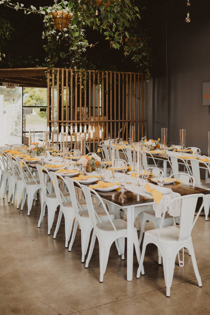 Modern Fall wedding reception with yellow napkins and white metal chairs at The Wood Shed in Vista California