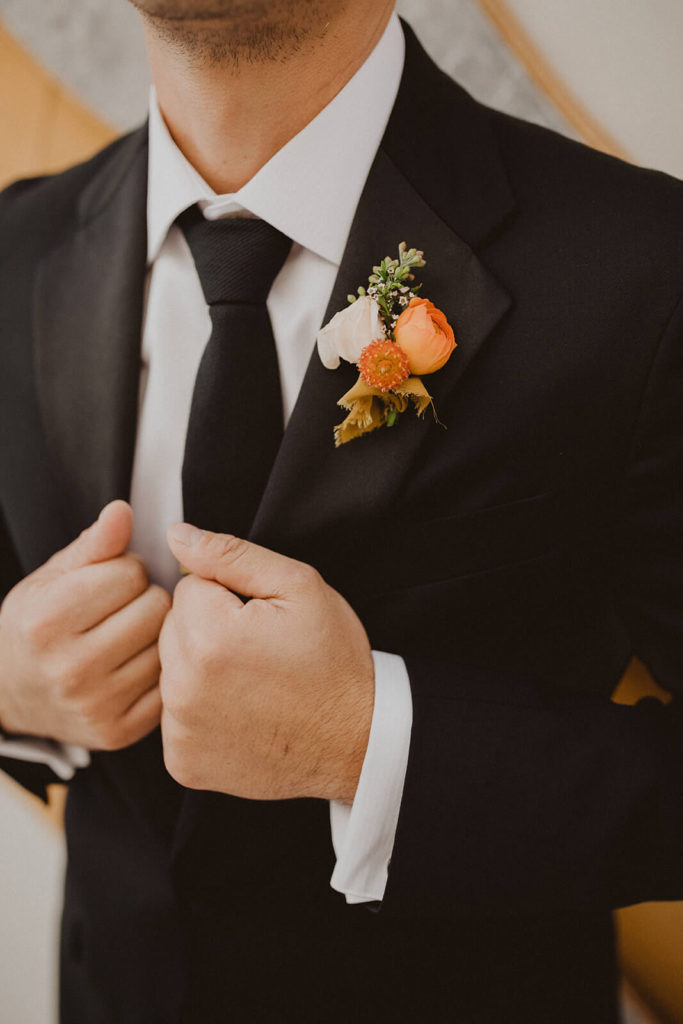 Fall wedding boutonniere with orange ranunculus 