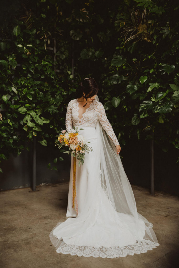 Fall wedding bride holding her colorful bouquet with orange yellow and mauve flowers at The Wood Shed in Vista California