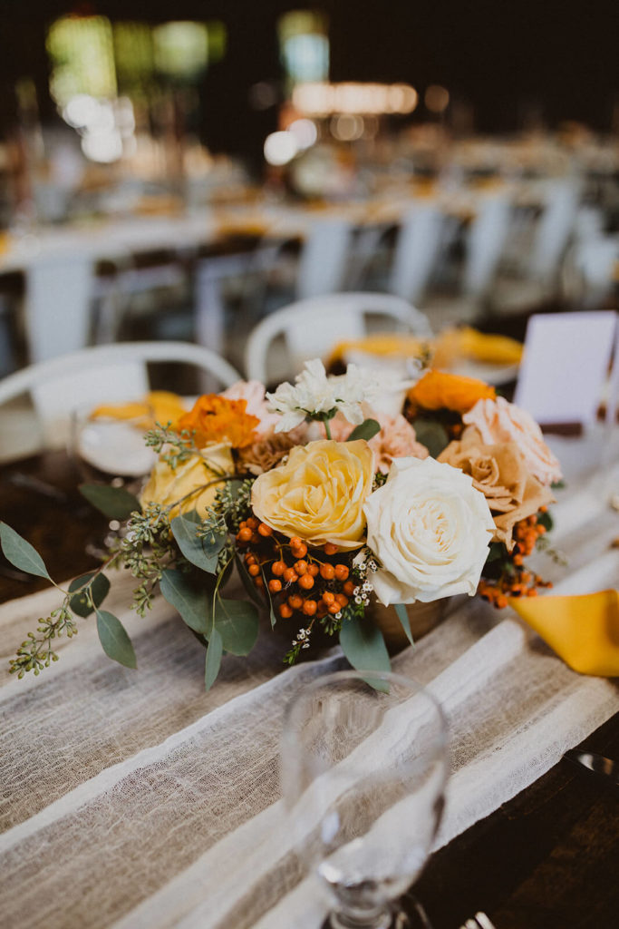 Fall wedding centerpiece with orange white and yellow flowers and citrus slices at The Wood Shed in Vista California 