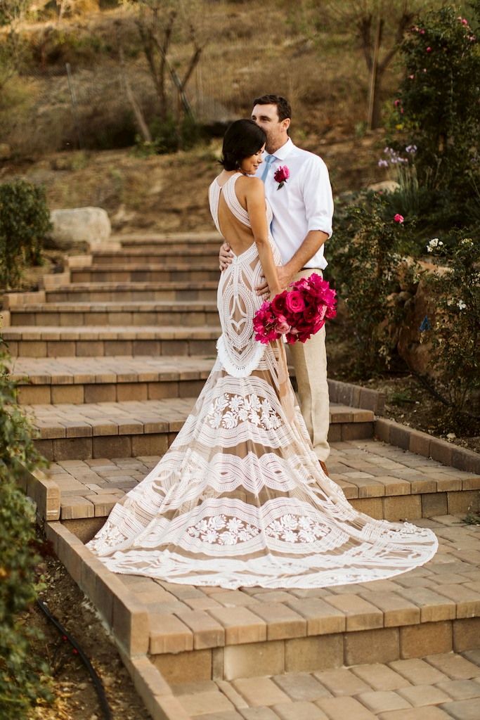 Fiesta inspired outdoor wedding bride in boho macrame dress with groom and pink flowers