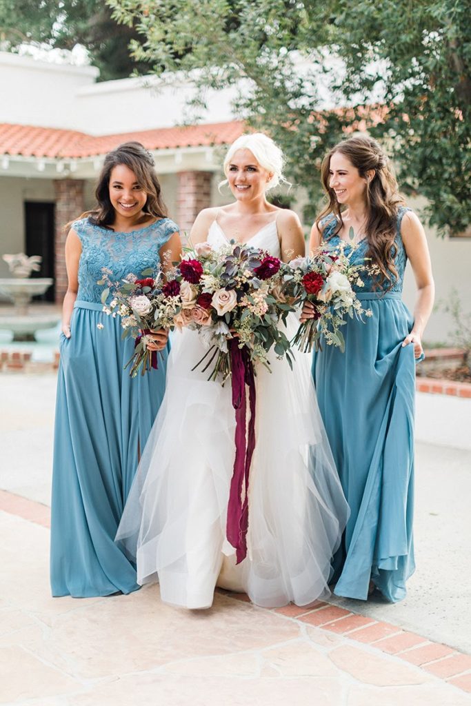 Organic blue and burgundy winter wedding bridal party wearing blue dresses with bouquets