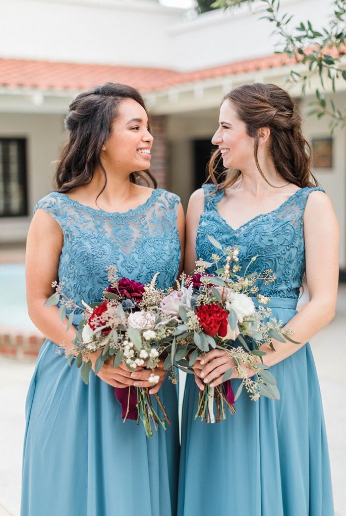 Organic blue and burgundy winter wedding bridesmaids in blue dresses holding bouquets