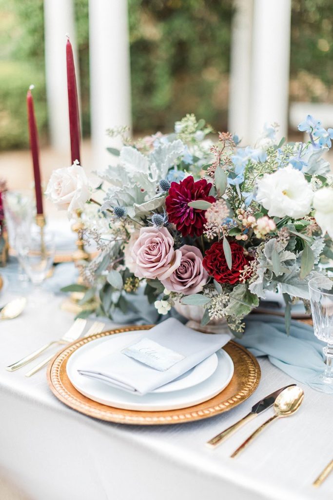 Organic blue and burgundy winter wedding centerpiece with gold silverware and blue linen at Orcutt Ranch