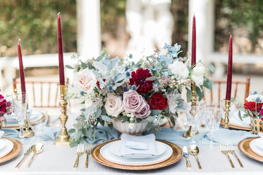 Organic blue and burgundy winter wedding centerpiece with gold silverware at Orcutt Ranch