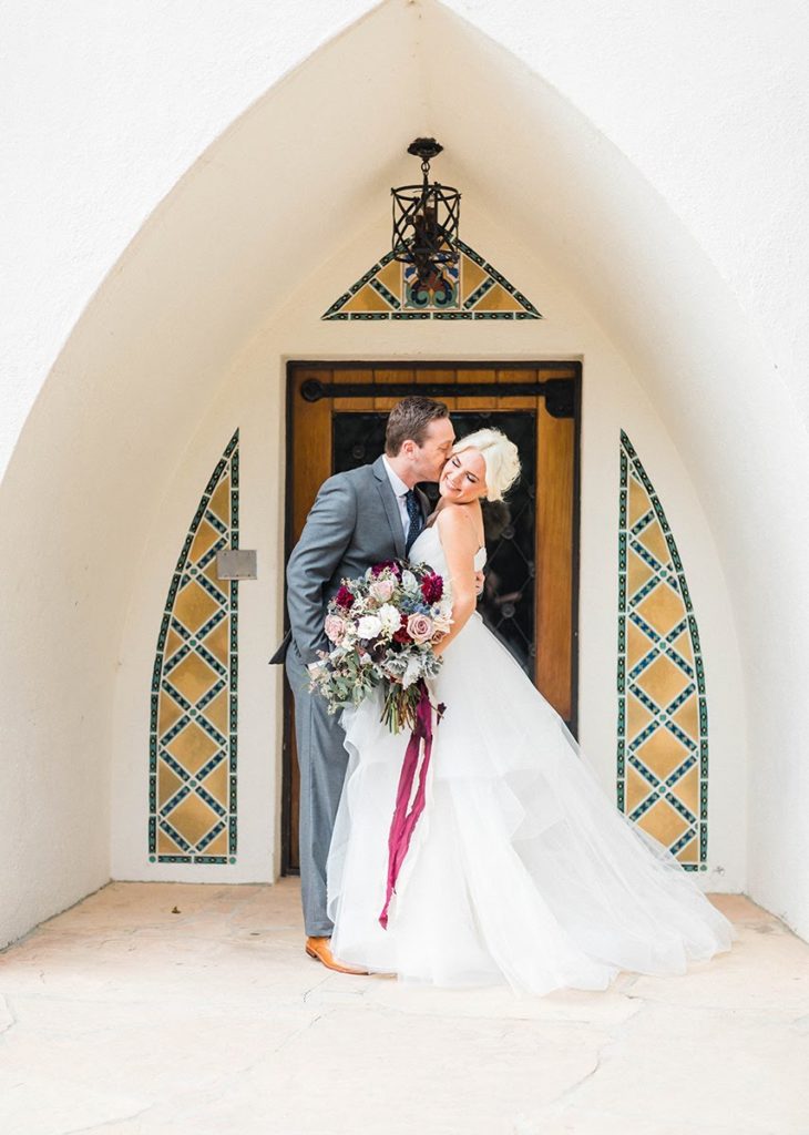Organic blue and burgundy winter wedding couple arch way with tiles at Orcutt Ranch