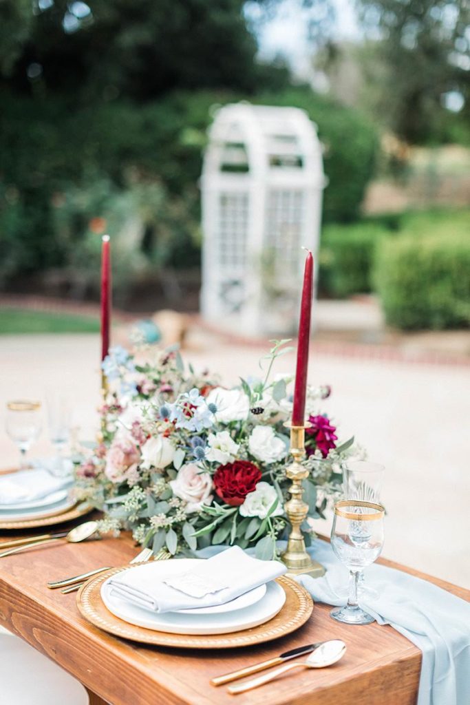 Organic blue and burgundy winter wedding sweetheart table flowers with gold candlesticks 