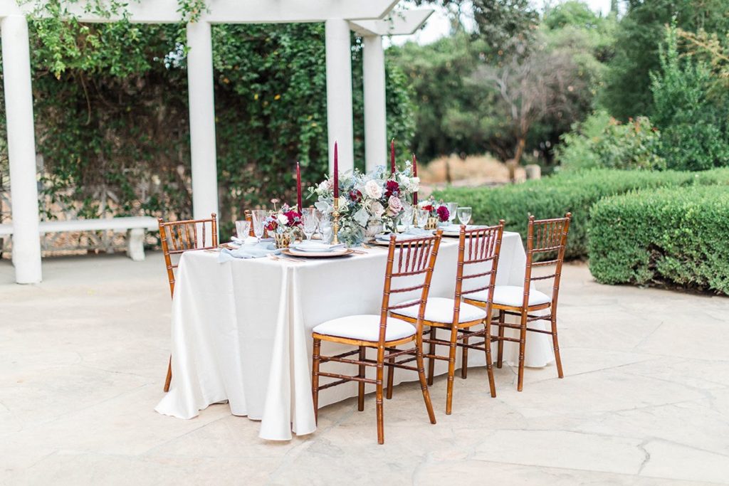 Organic blue and burgundy winter wedding reception table with brown chiavari chairs at Orcutt Ranch
