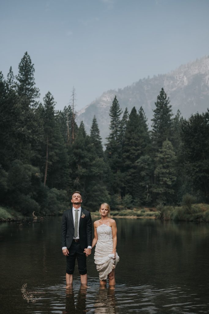 Bride and groom standing in a river in Yosemite 