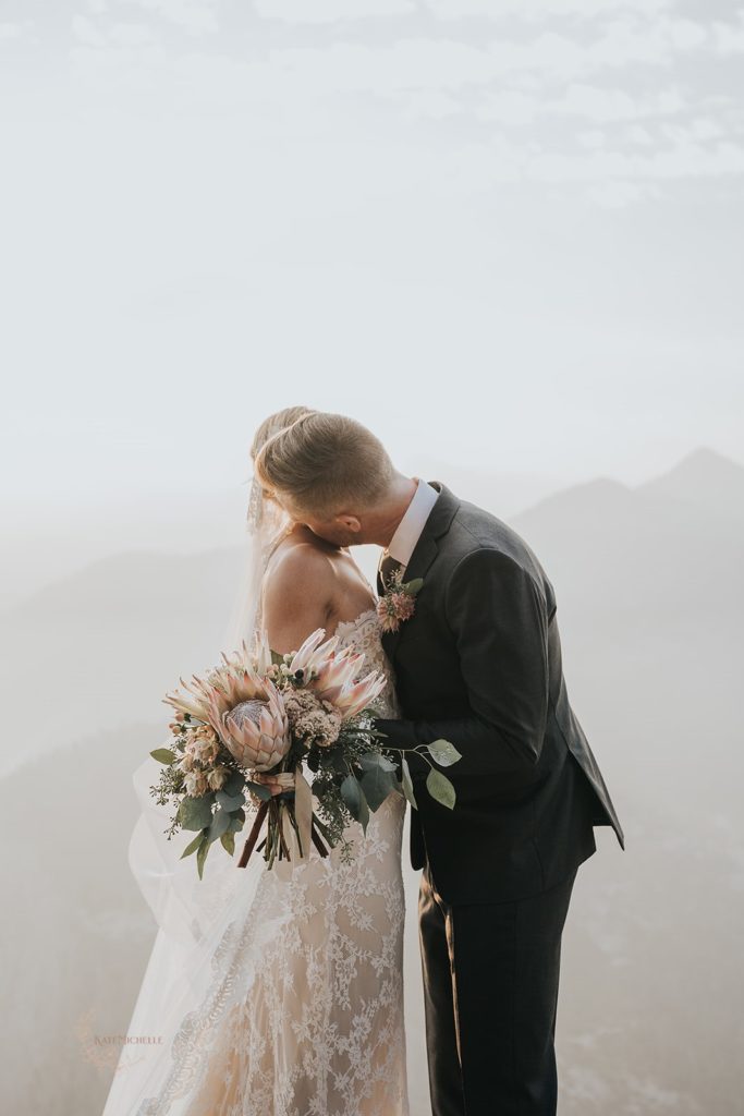 Groom and bride holding a large protea bouquet hugging at their elopement in Yosemite 