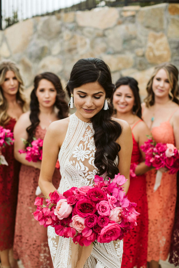 Outdoor pink bougainvillea wedding Latina bride holding a pink bouquet with her bridesmaids wearing colorful dresses