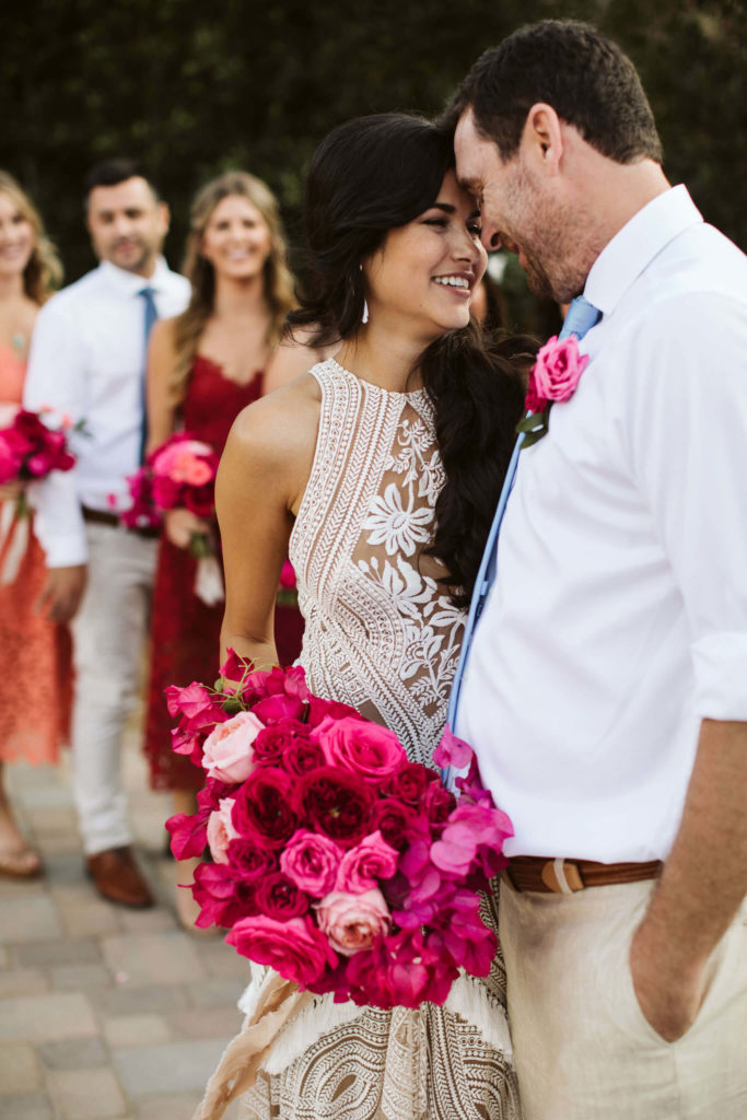 Outdoor pink bougainvillea groom and Latina bride with a pink bouquet