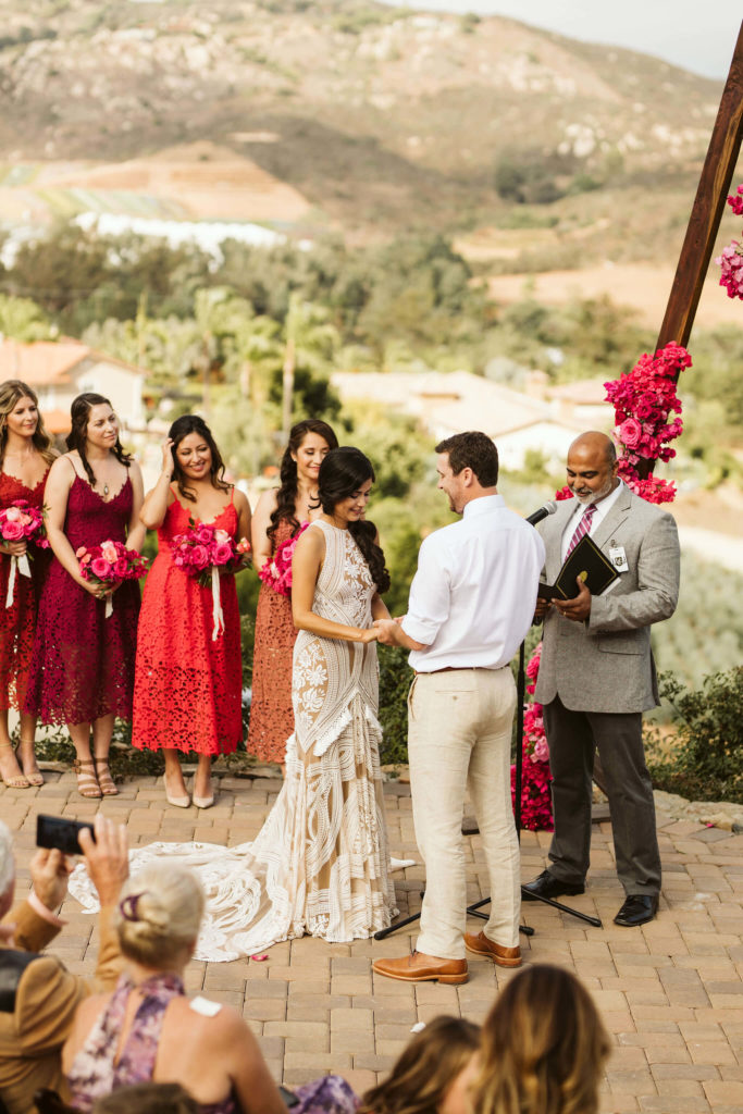 Outdoor pink bougainvillea wedding groom and Latina bride with bridesmaids wearing colorful dresses
