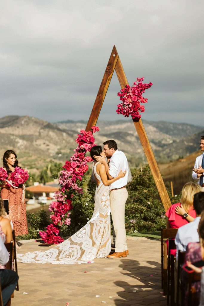 Fiesta inspired outdoor wedding ceremony with a triangle arch and pink flowers