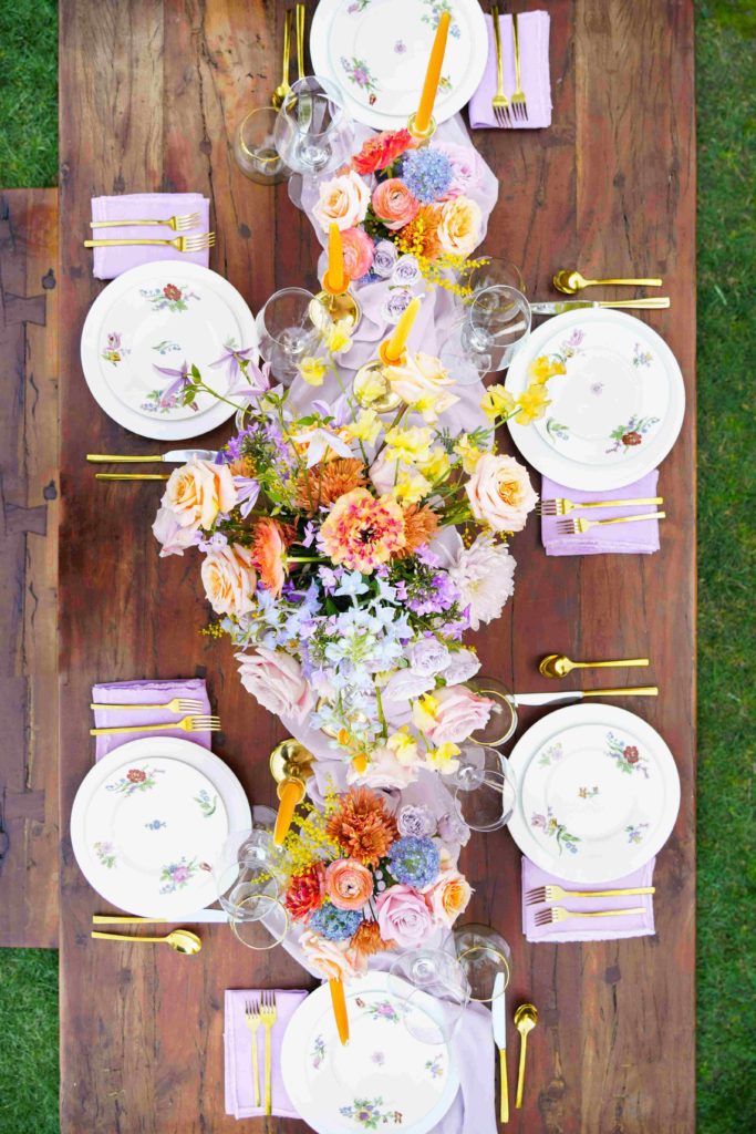 Colorful wedding reception table with lavender linen and yellow taper candles