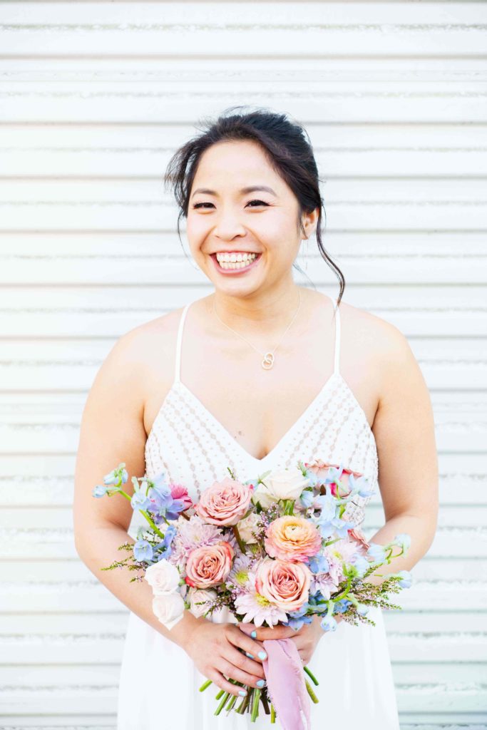 Bride smiling while holding her colorful wedding bouquet