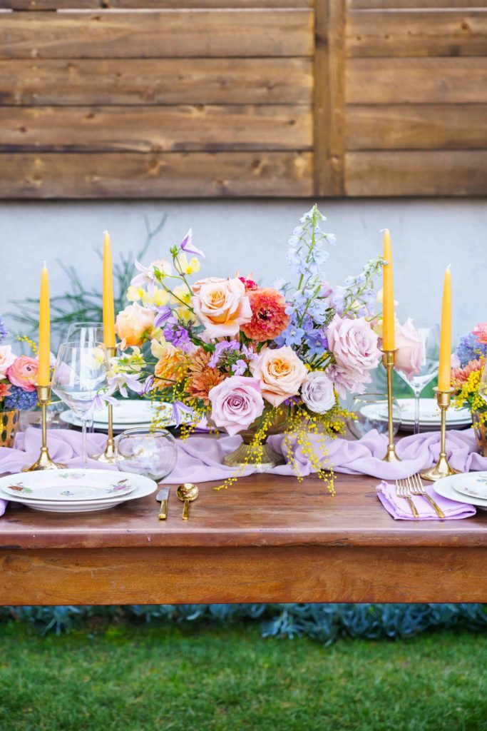 Colorful pastel wedding centerpiece with yellow taper candles