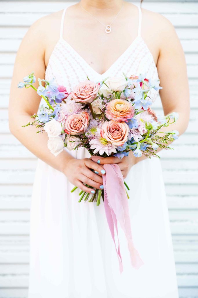Colorful pastel wedding bouquet with pink ribbon