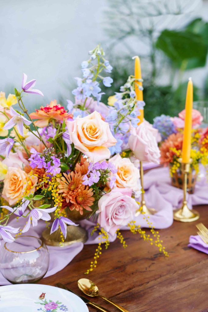 Colorful wedding centerpiece with pastel flowers on a lavender table runner