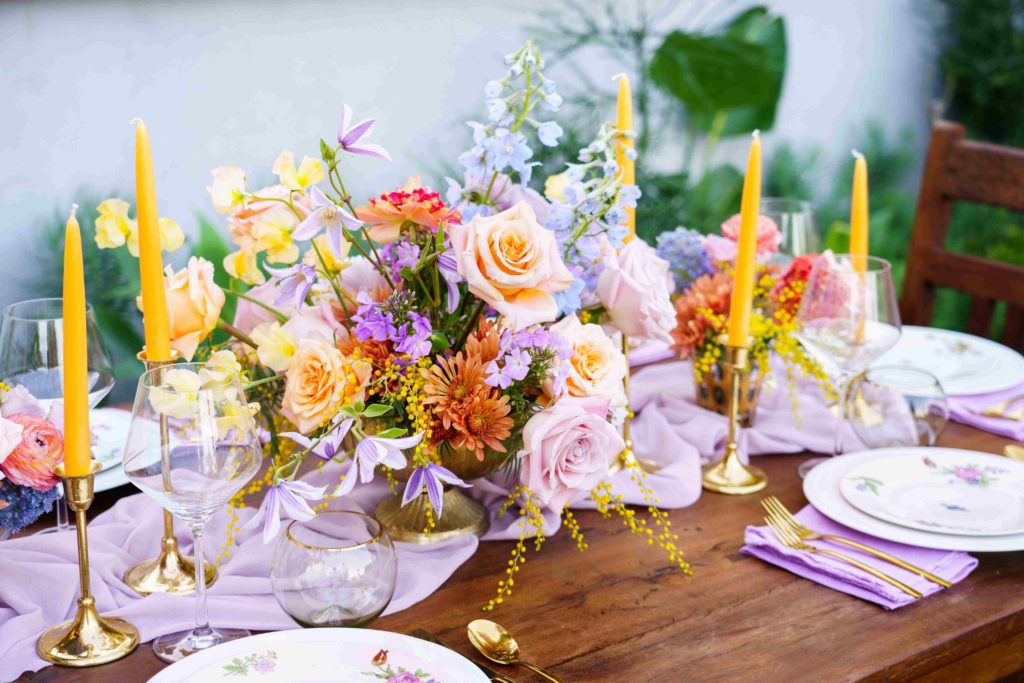 Colorful wedding reception centerpiece with lavender linen and yellow taper candles