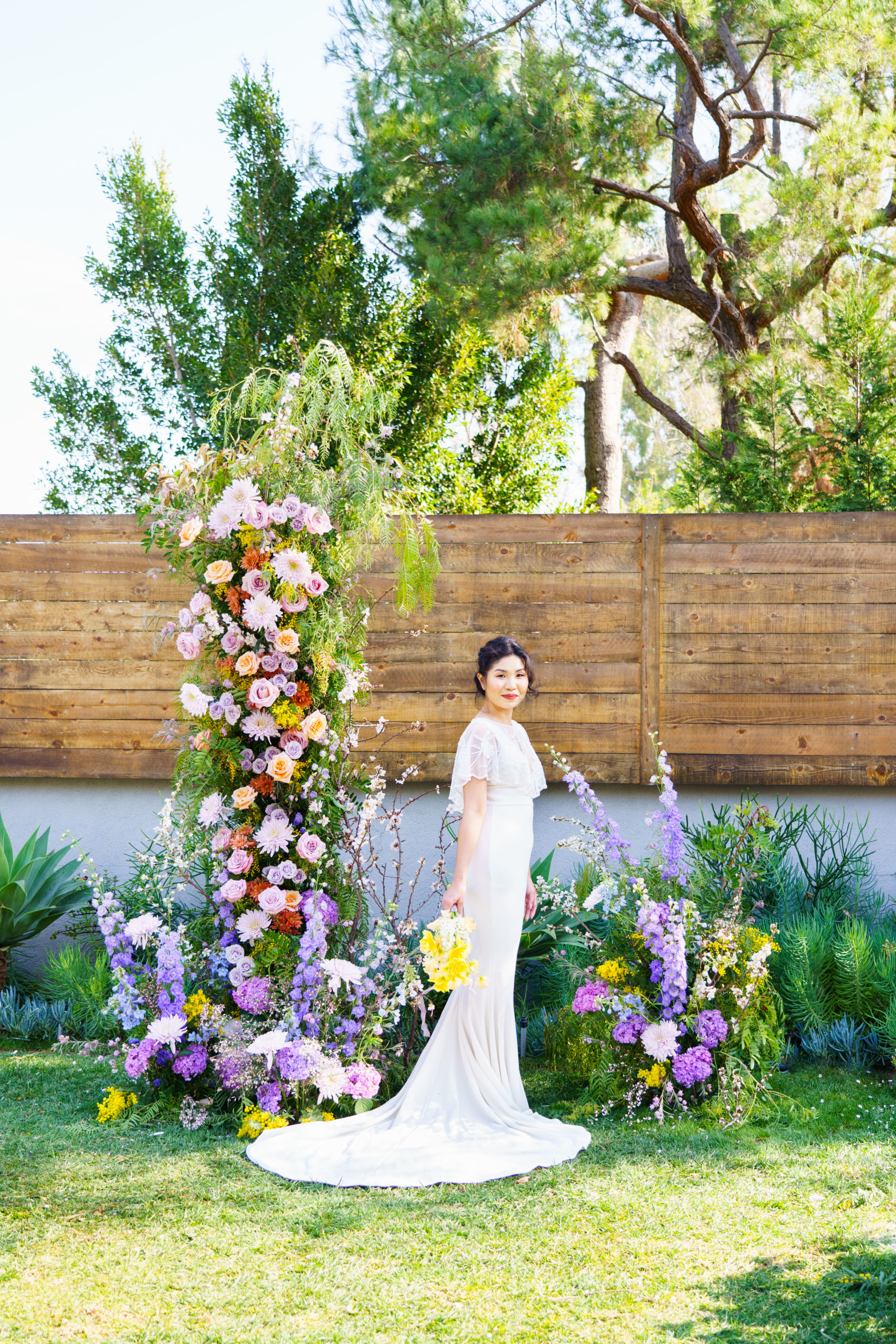 Colorful Spring garden inspired wedding arch with a beautiful Asian bride holding a bouquet