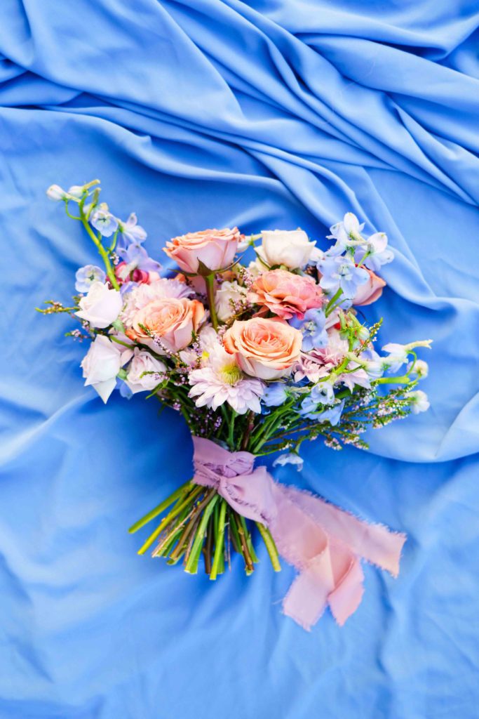 Colorful pastel wedding bouquet on bright blue linen