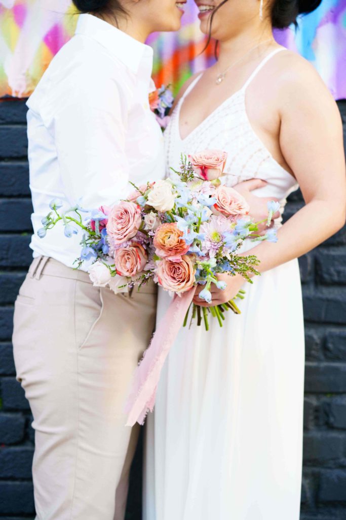 Lesbian couple holding a colorful bouquet 