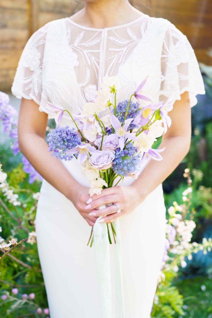 Bride holding a small spring bouquet with clematis and purple flowers
