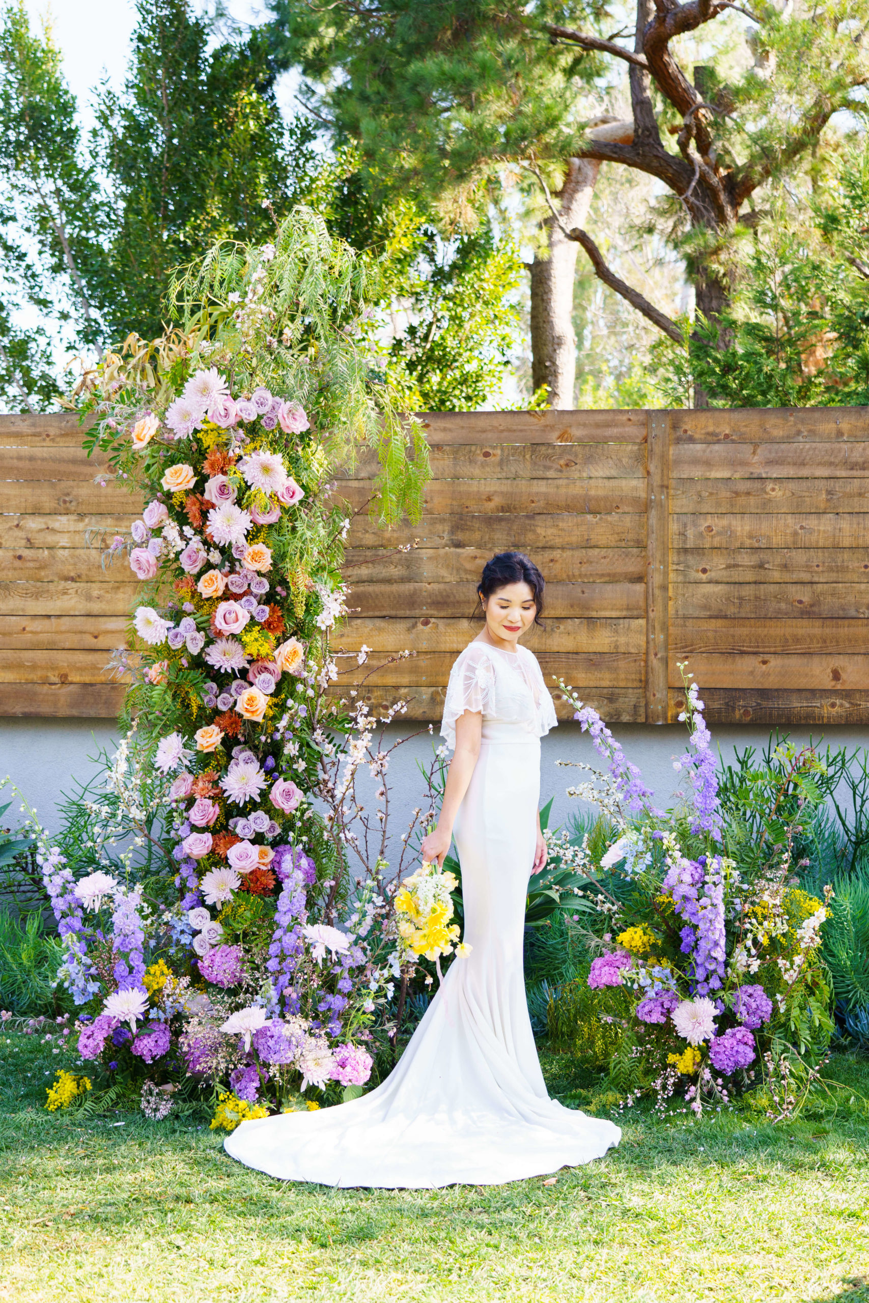 Bride standing in front of Bridgerton inspired colorful floral arch