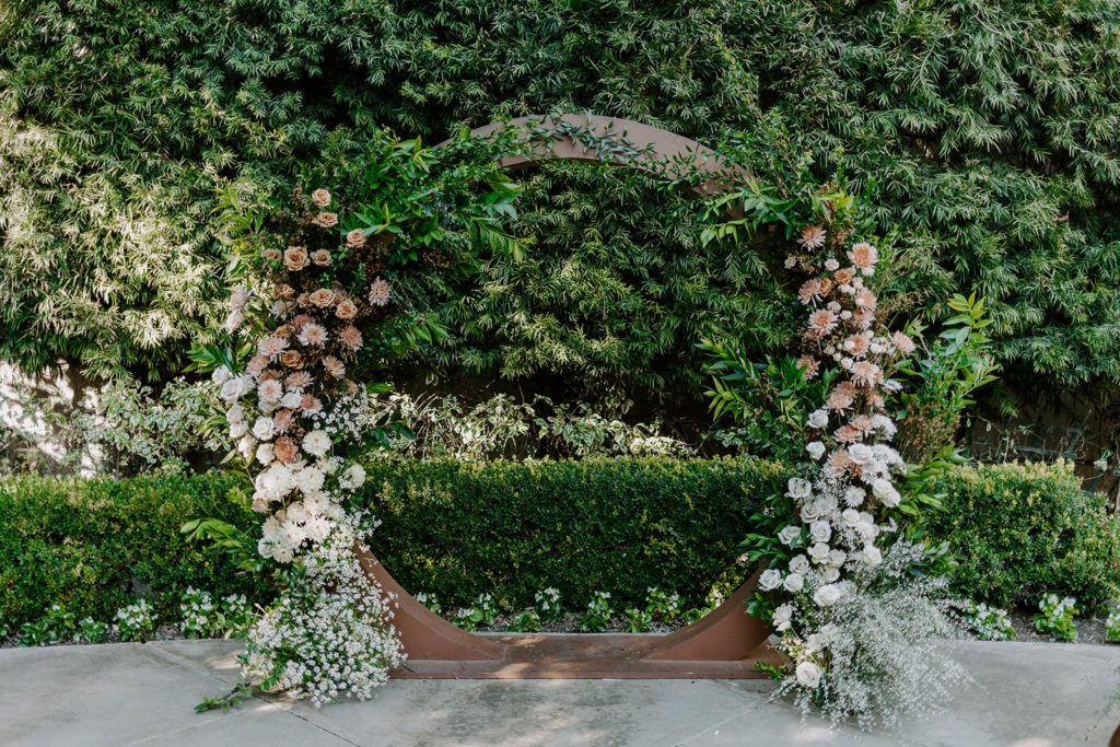 Wooden circle arch for wedding ceremony with peach and cream flowers