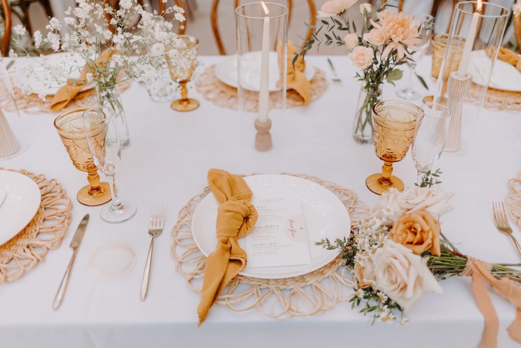 Wedding reception table decor with peach colors, fresh florals, and taper candles