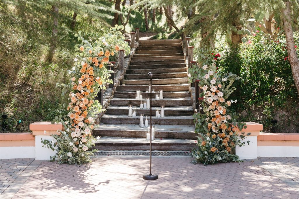 Floral wedding arch in front of staircase with candles at Rancho Las Lomas wedding ceremony