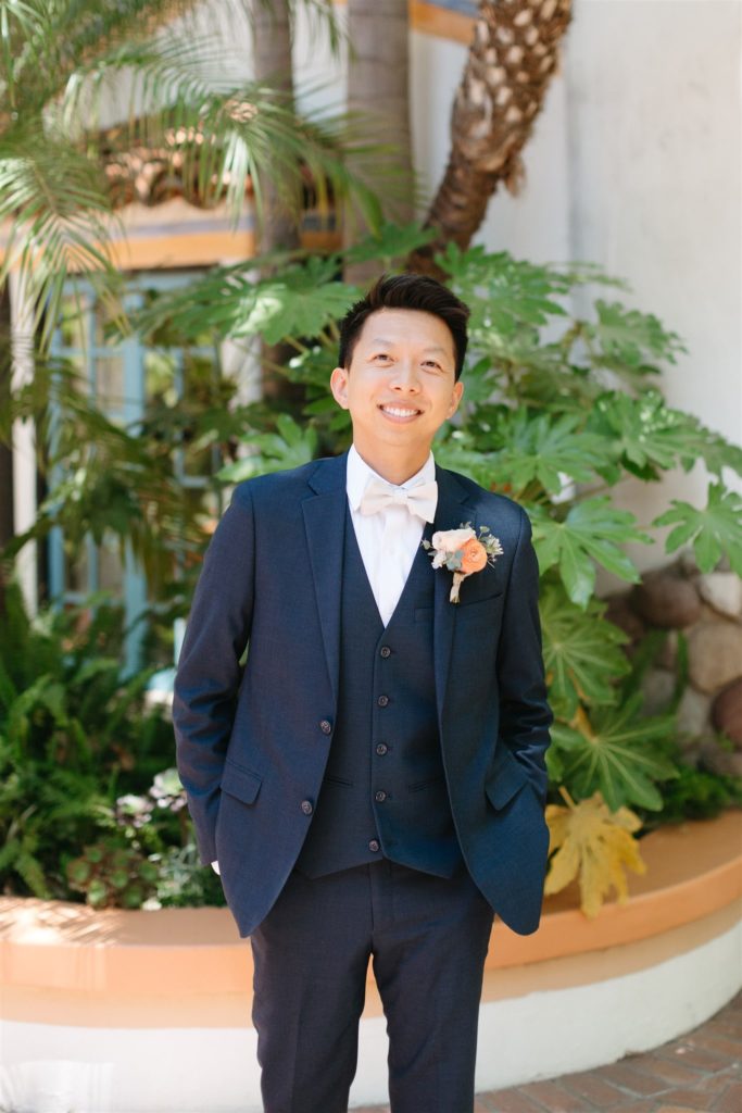 Groom wearing navy tux with peach and cream boutonniere