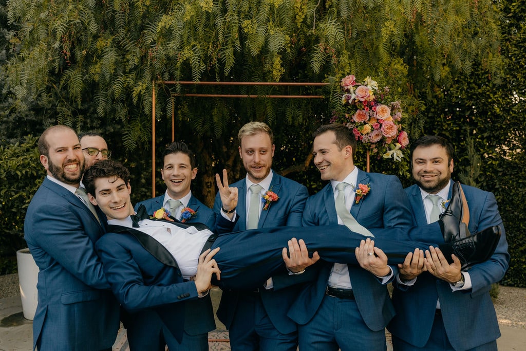 Groom and groomsmen smiling at Los Angeles wedding wearing navy suits