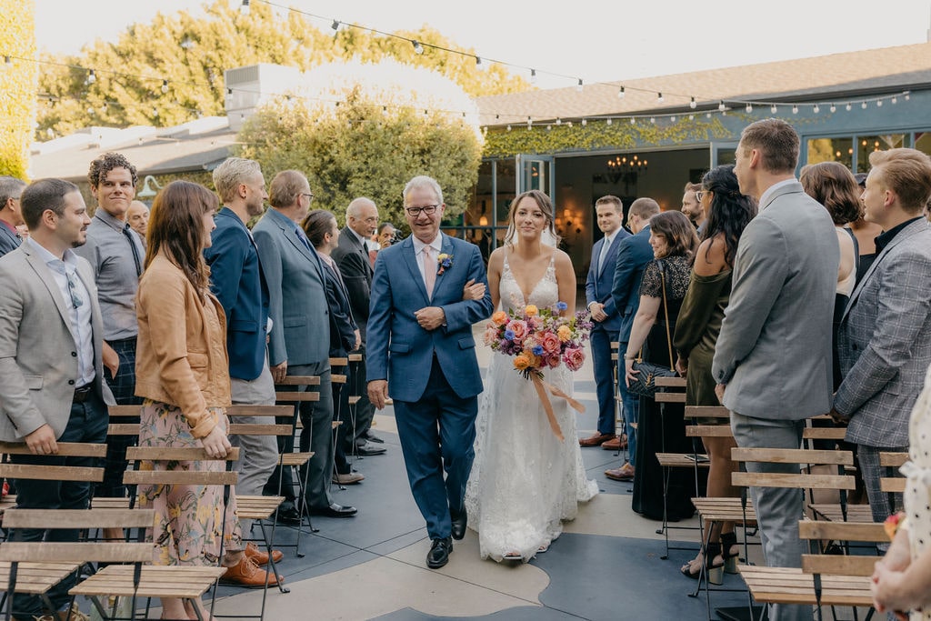 Bride and father walking down aisle at outdoor ceremony in Los Angeles