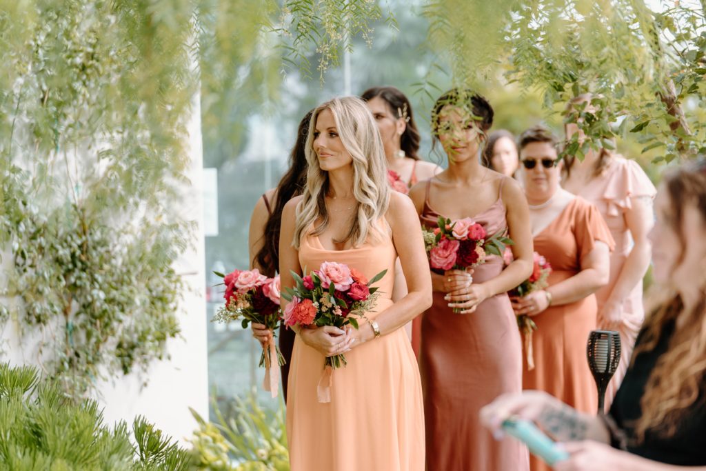 Bridesmaids wearing orange dresses during ceremony