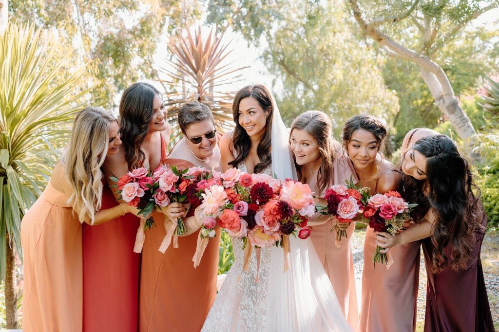 Bride and bridesmaids with pink, red, and orange bouquets
