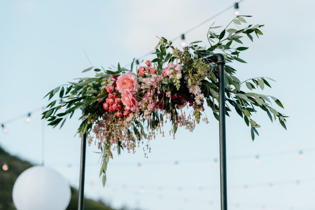 Metal wedding arch with greenery and pink flowers
