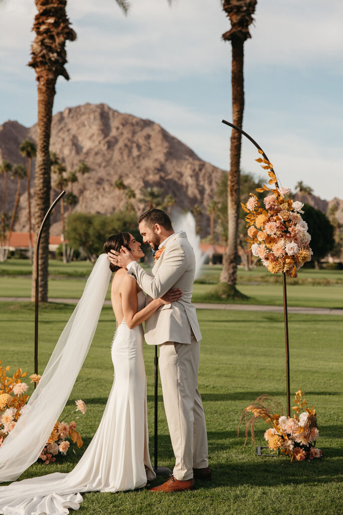 Bride and groom kissing at their wedding ceremony arch at La Quinta Resort