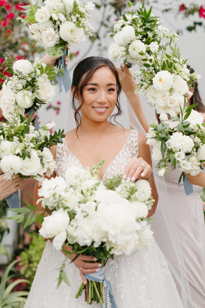 Bride holding a bouquet with white peonies surrounded by her bridesmaid's bouquets
